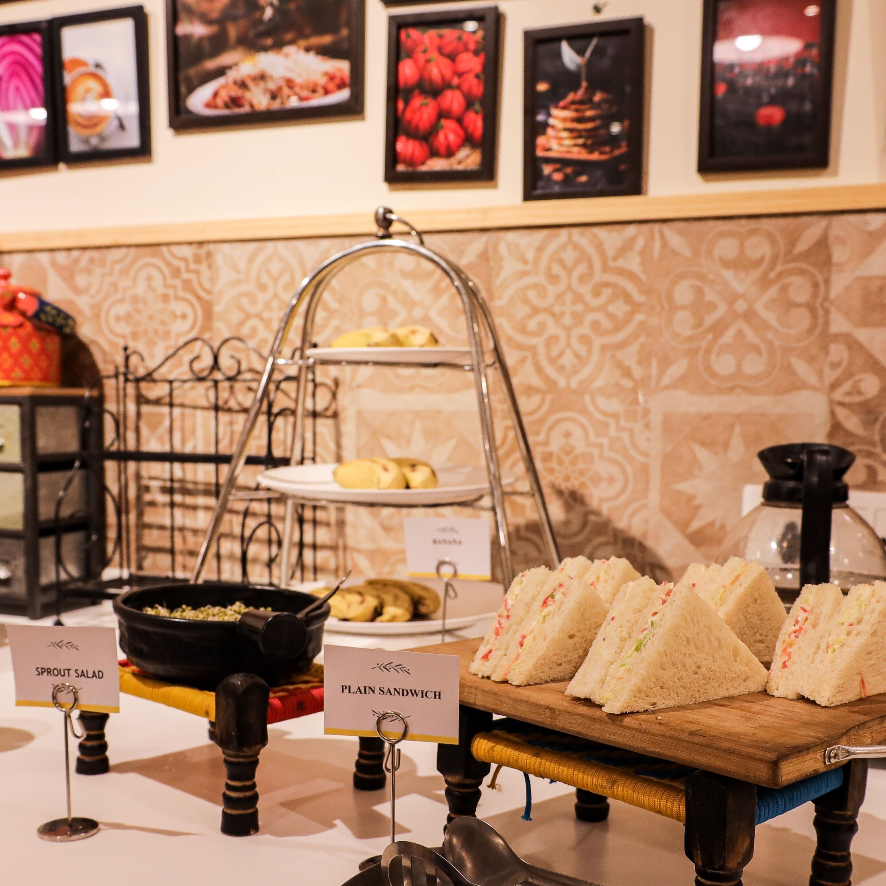 A buffet setup with labeled food items including sprout salad and plain sandwiches.