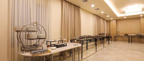 Una sala de conferencias con una larga mesa, sillas y mesas de buffet.