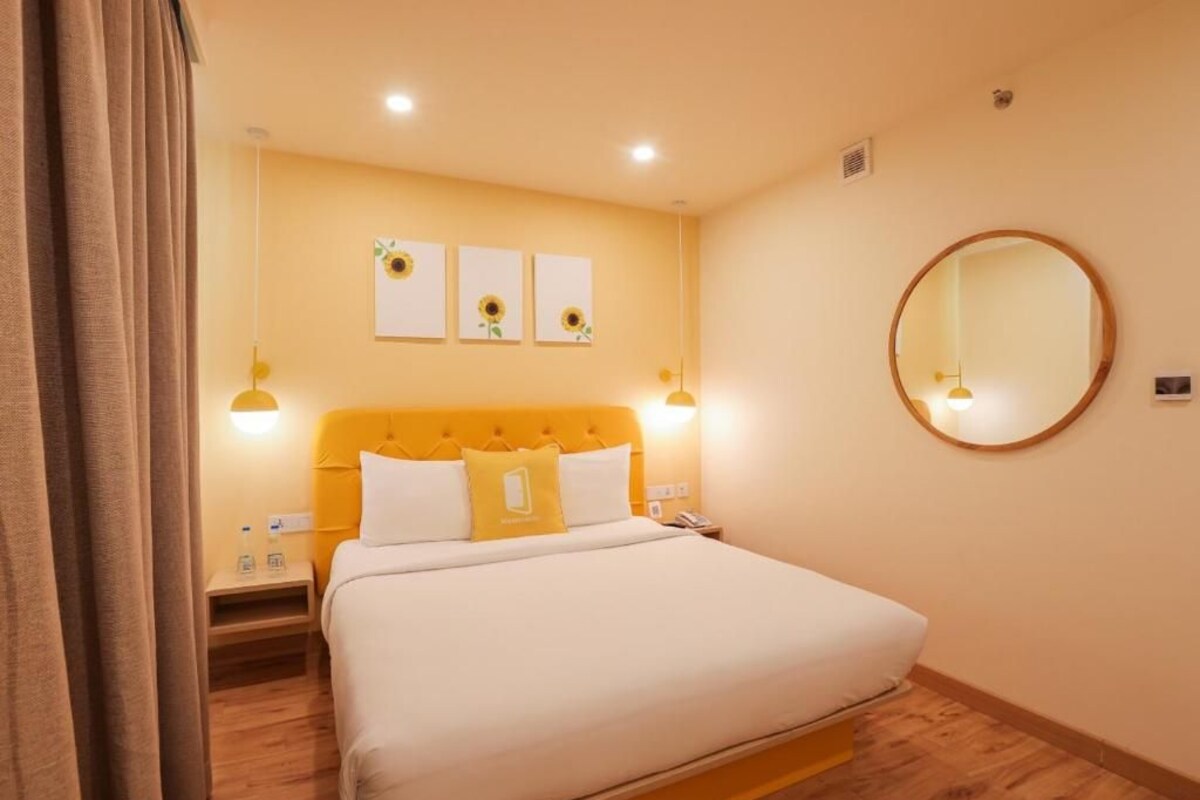 Een hotelkamer met een bed, nachtlampjes, een ronde spiegel en wanddecoratie.