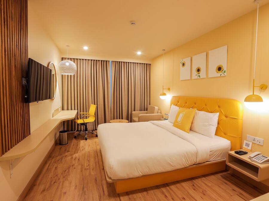 Una camera d'albergo con un letto grande, una scrivania, una sedia, una televisione e una finestra con tende.