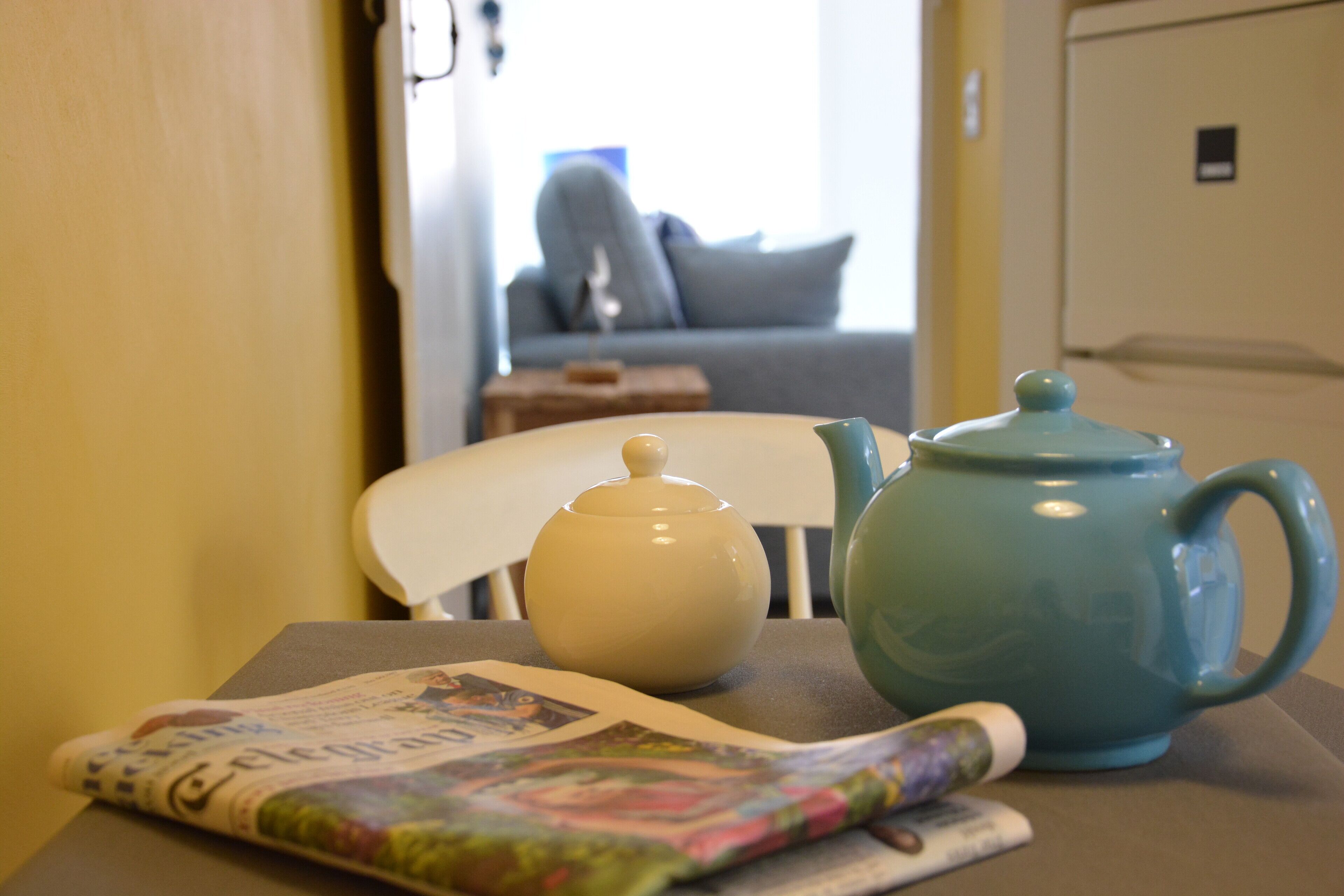 Une table avec une théière, une tasse et un journal.