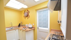 Een kleine keuken met een spoelbak, aanrecht en kookplaat.