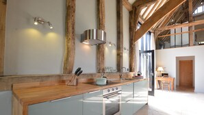 A modern kitchen with a wooden countertop, stainless steel appliances, and exposed wooden beams. - Manor House Barn, Peasenhall (Saxmundham)
