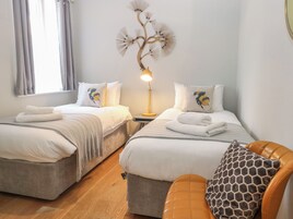 Habitación de hotel con dos camas, una lámpara, un cojín estampado con diseño de jirafa y piso de madera.