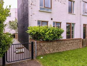 A residential building with a brick facade, a stone wall, and a metal gate. - The Hive, Southwold (Reydon)