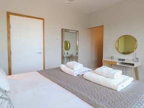 Et hotelværelse med seng, badeværelse med spejl og et natbord.