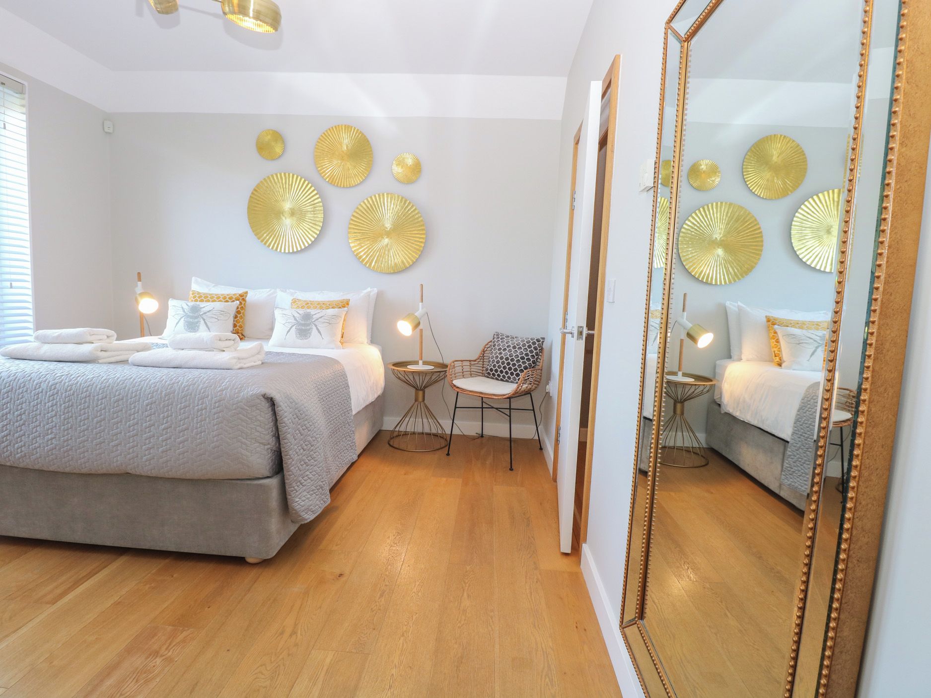 A bedroom with a bed, bedside tables, a chair, a mirror, and wall decorations.