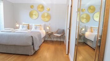 A bedroom with a bed, bedside tables, a chair, a mirror, and wall decorations.