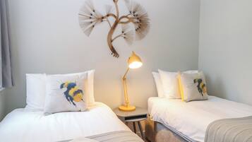 A hotel room with two beds, a bedside table with a lamp, and a wall decoration.