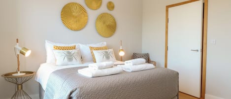 A bedroom with a bed, bedside tables, and decorative wall art.