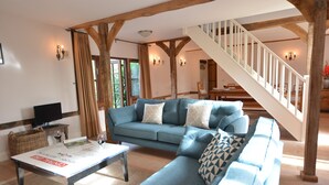 A living room with a blue sofa, a coffee table, and a staircase. - Wheelwright's Barn (Halesworth)