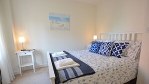 Ein ordentlich eingerichtetes Schlafzimmer mit einem Bett, Nachttischen und einem Bild an der Wand.