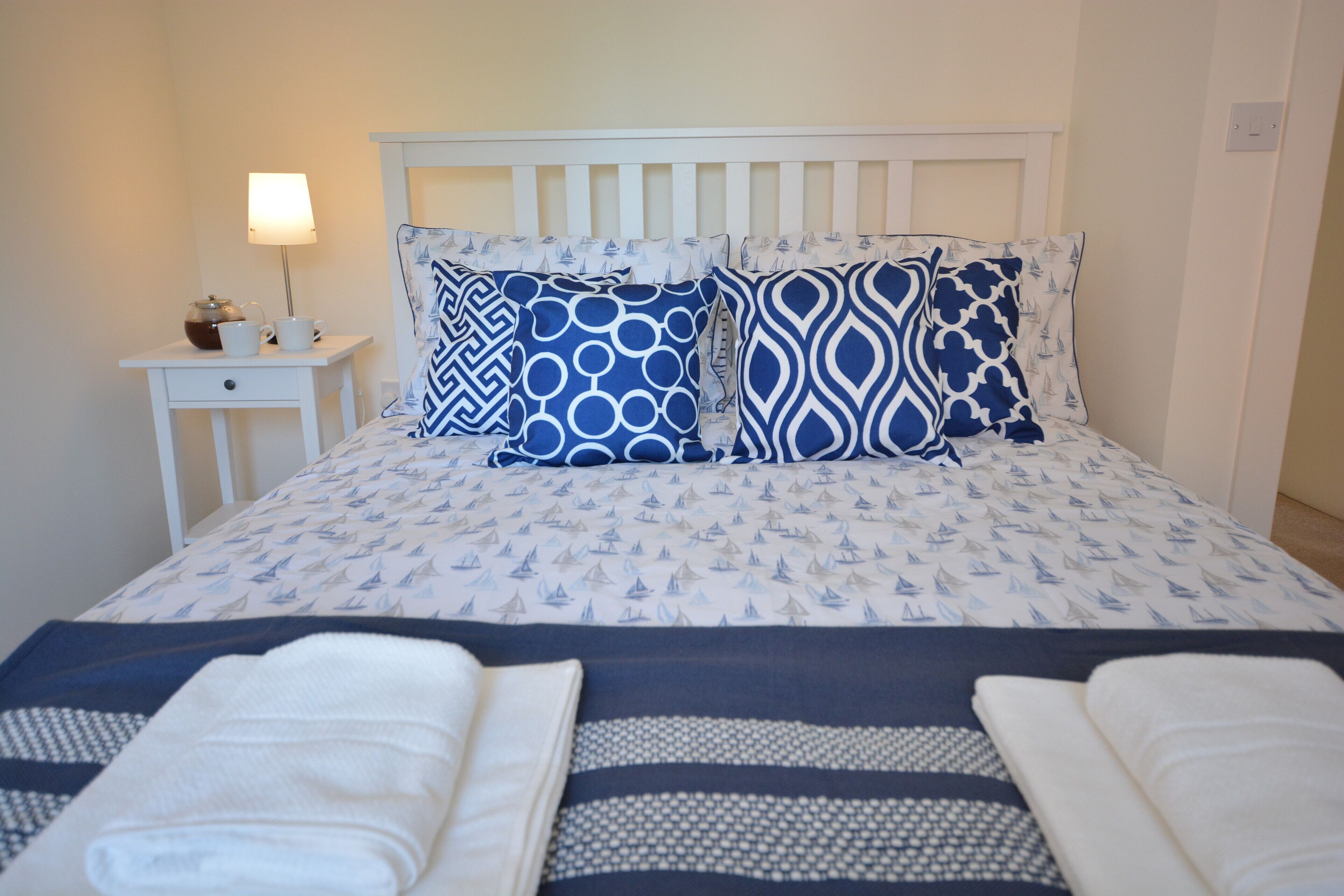 A neatly made bed with a patterned bedspread, two pillows, and two folded towels.