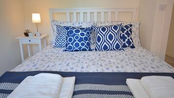 A neatly made bed with a patterned bedspread, two pillows, and two folded towels.
