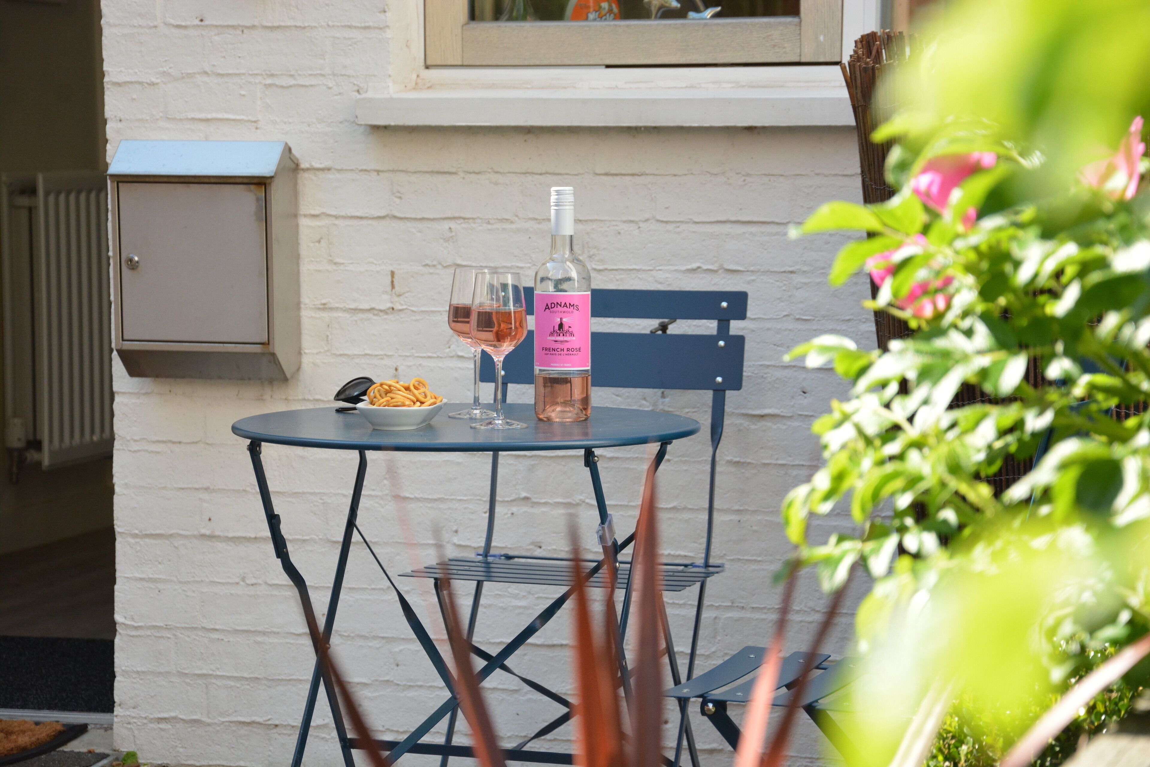 A table with a bottle of French rosé wine, two glasses, and a bowl of fries.