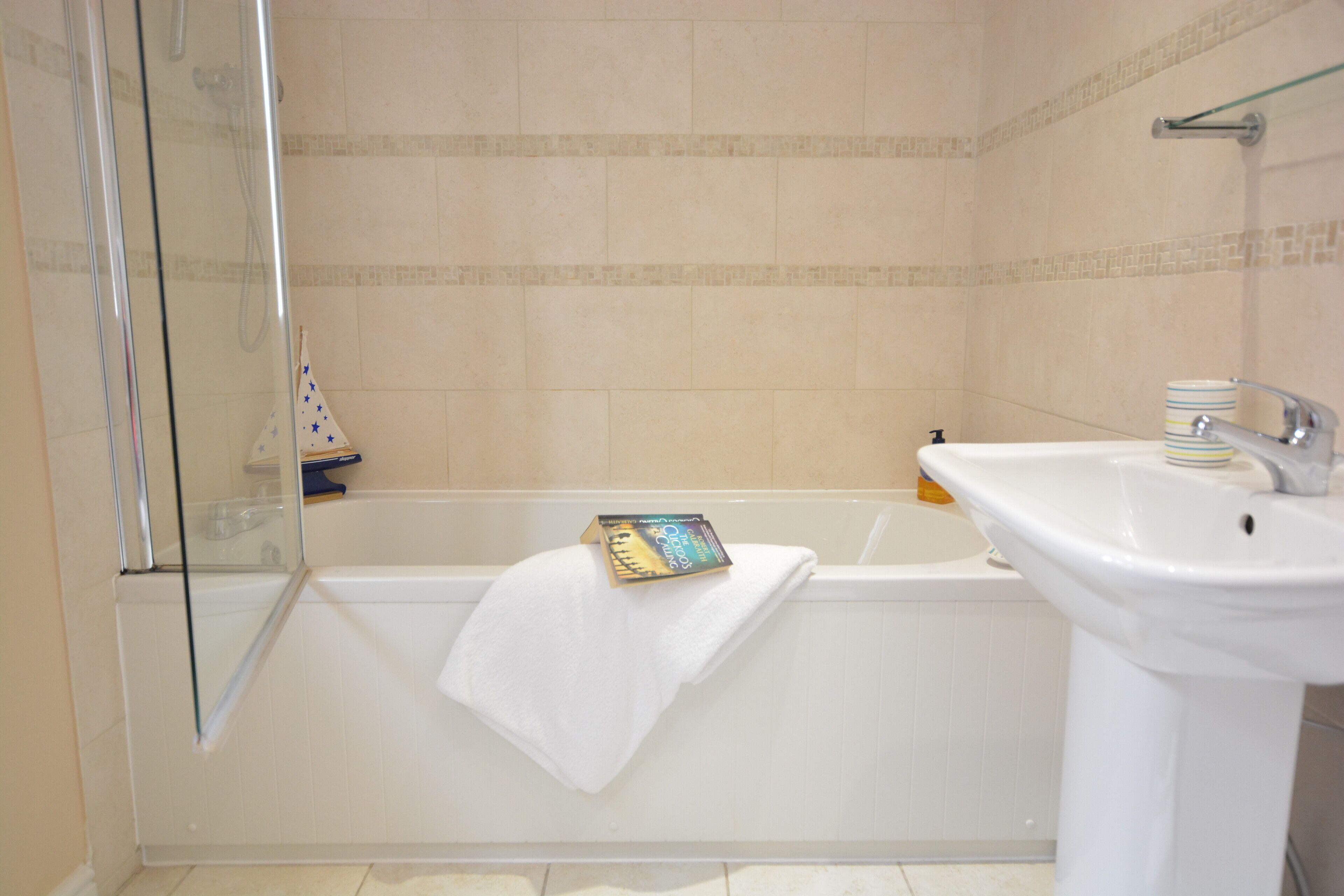 A bathroom with a glass shower enclosure, a bathtub, and a white sink.