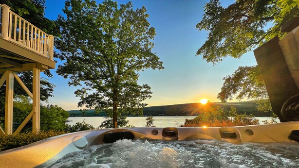 A hot tub with a view of a lake and sunset.