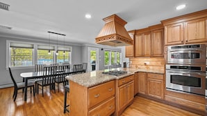 A modern kitchen with wooden cabinets, a granite countertop, and stainless steel appliances.