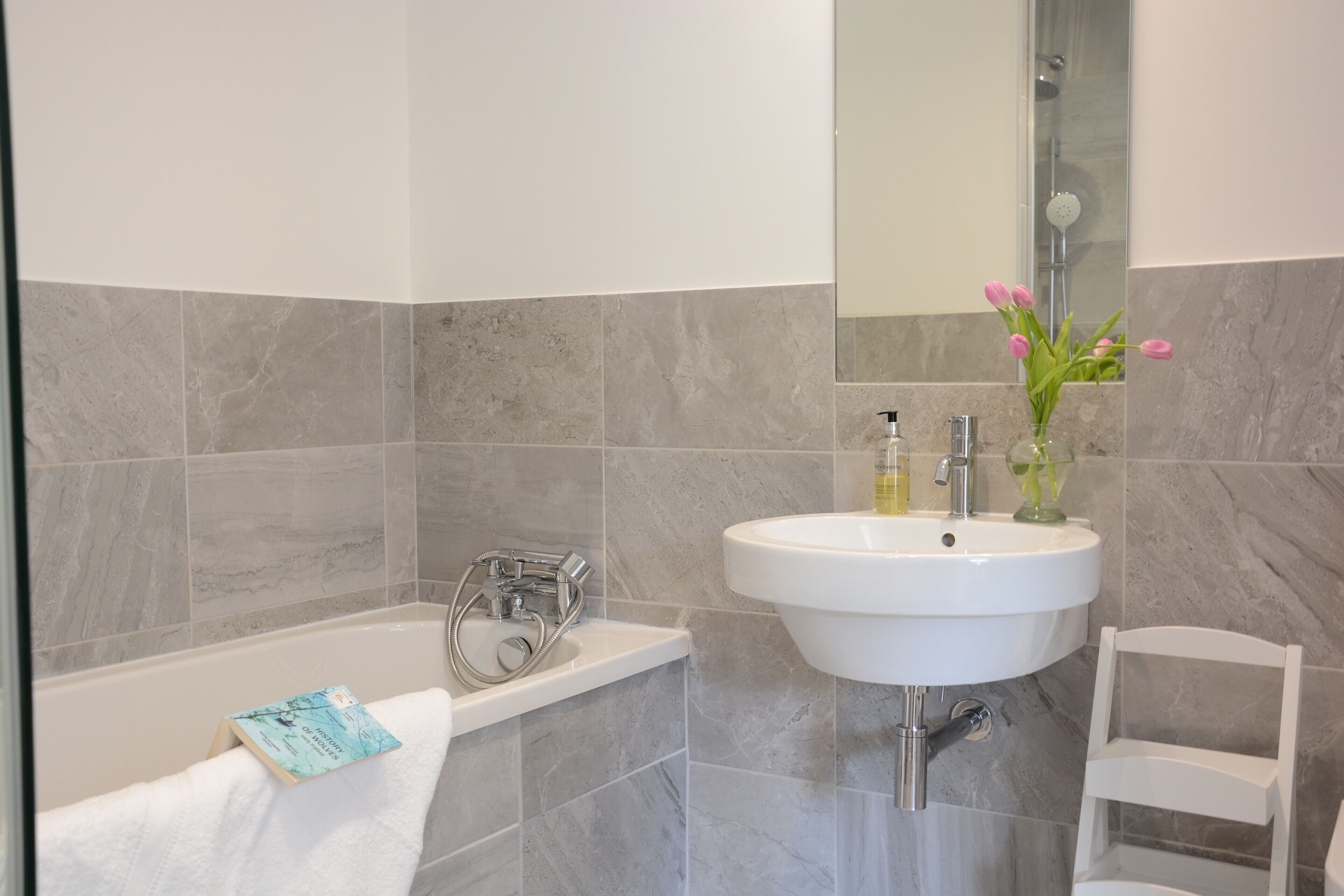 A bathroom with a bathtub, a sink, and a mirror.