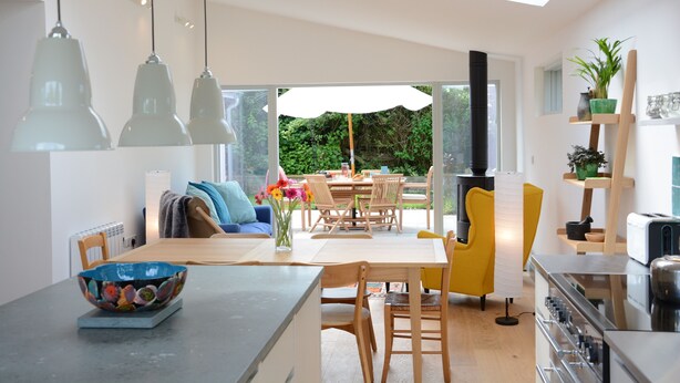 Una cocina moderna con comedor, una silla amarilla y un ventanal grande.