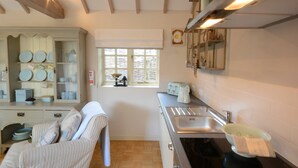 A kitchen with a wooden cabinet, a window, a sink, and a toaster. - The Nookery at Snape Hall (Saxmundham)