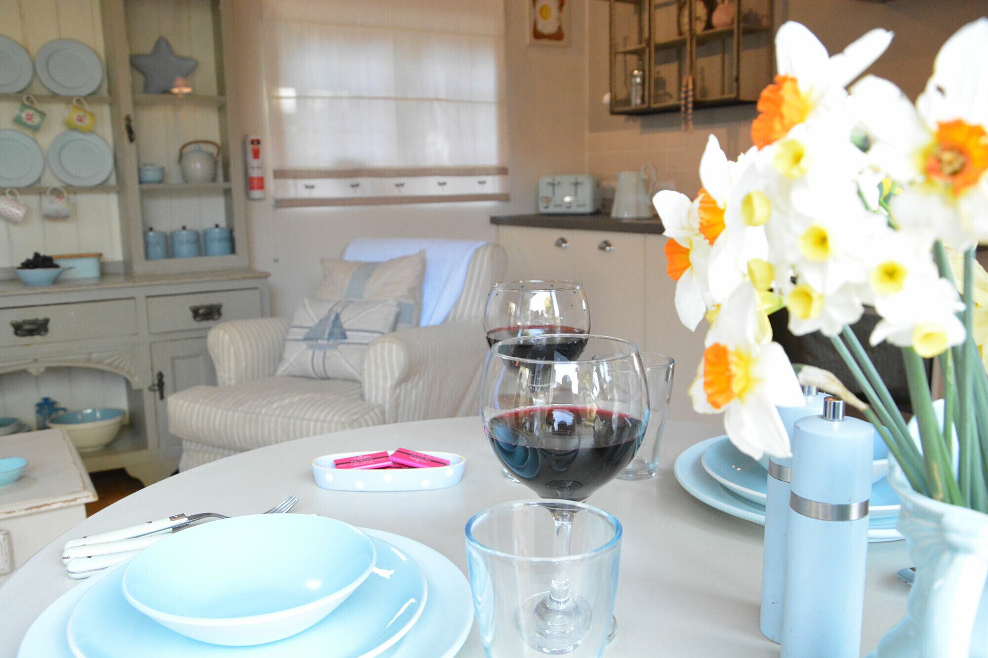 A dining table with blue plates, a wine glass, and a vase with flowers.