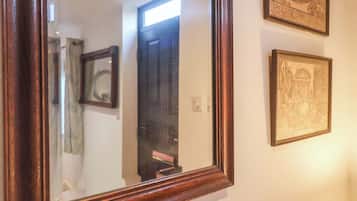 A mirror with a wooden frame, a door, and two framed pictures on the wall.