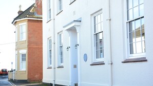 A row of white buildings with a red brick section, a white door, and a blue plaque. - Skimming Stones, Aldeburgh (Aldeburgh)