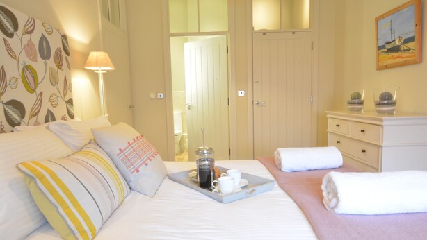 A hotel room with a bed, a tray with a coffee pot, cups, and towels. - Skimming Stones, Aldeburgh (Aldeburgh)