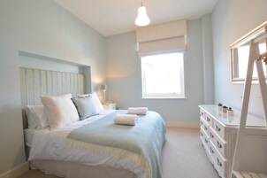 Un dormitorio con cama, mesitas de noche, cómoda y ventana.