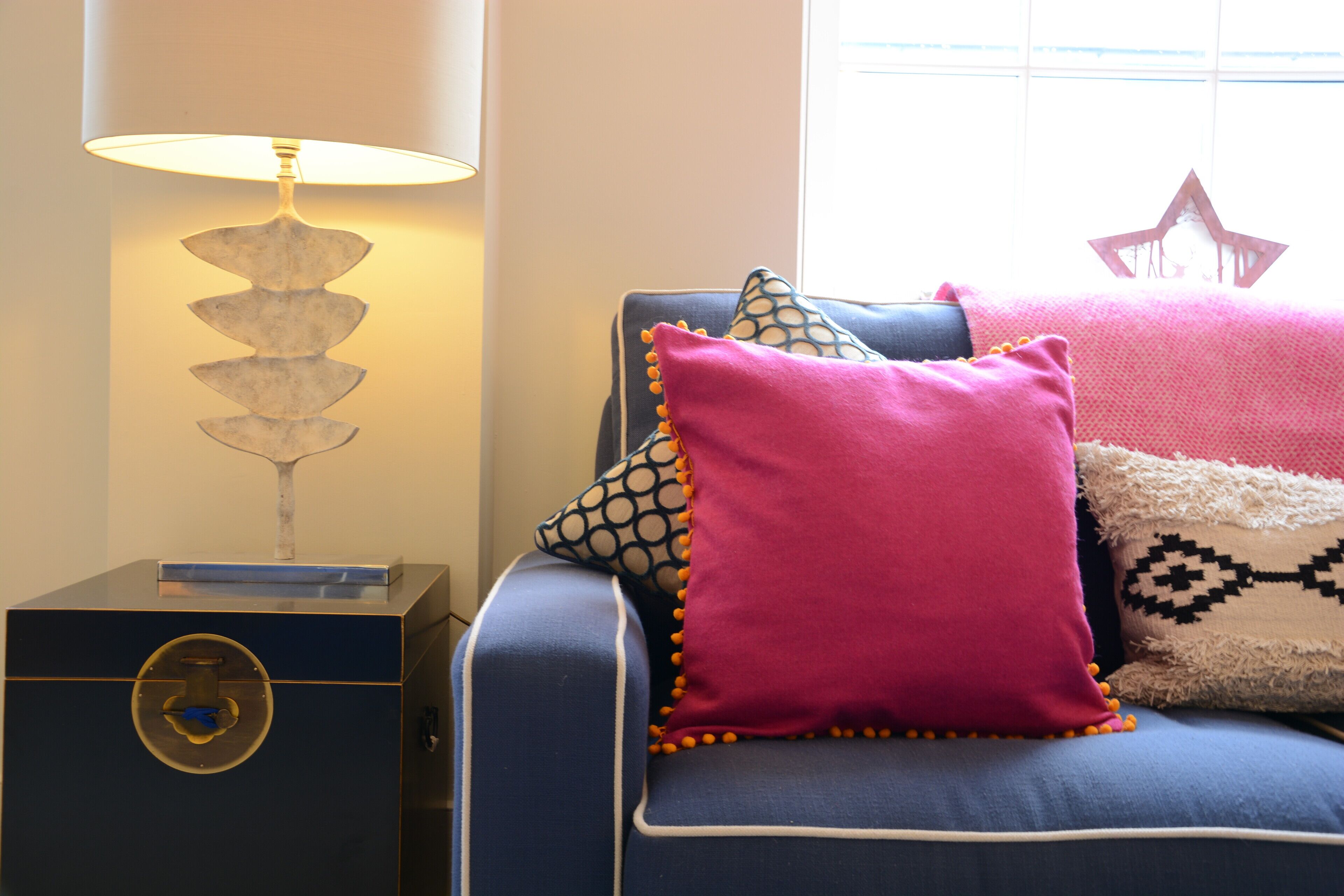A blue sofa with multiple pillows, a lamp, and a decorative star on the wall.