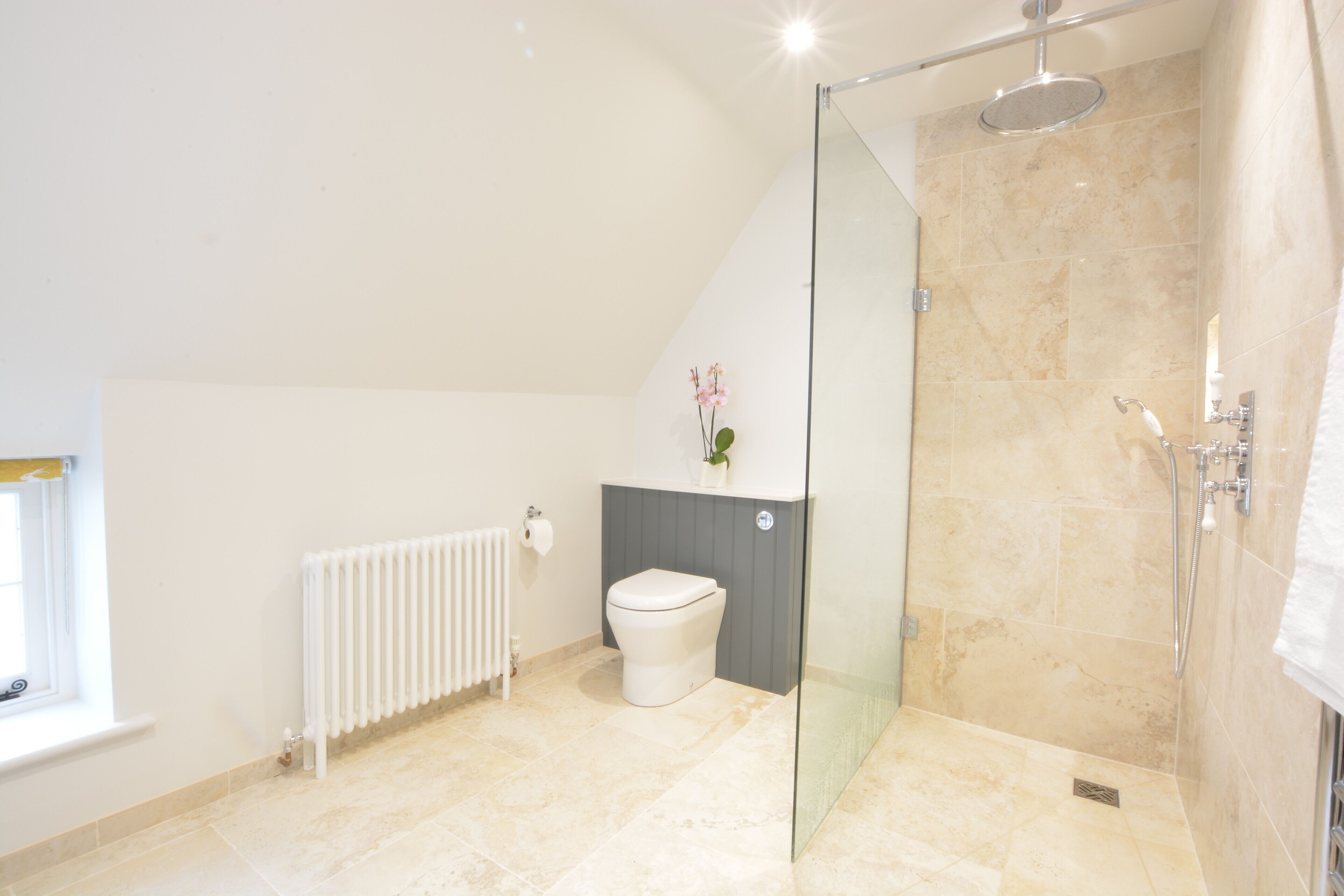 A modern bathroom with a glass-enclosed shower, a white toilet, and a radiator.