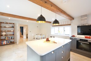 A modern kitchen with a central island, pendant lighting, and a built-in oven. - Woodland Cottage, Great Glemham (Saxmundham)