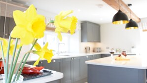 A modern kitchen with a central island, grey cabinets, and hanging pendant lights. - Woodland Cottage, Great Glemham (Saxmundham)