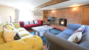 A cozy living room with a fireplace, a red sofa, a yellow sofa, and a grey sofa.