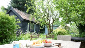 A wooden table with breakfast items, two chairs, and a rustic building in the background.