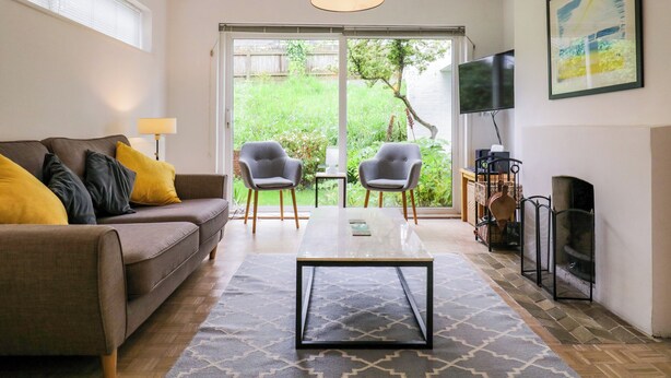 A living room with a sofa, two chairs, a coffee table, a TV, and a fireplace. - The Bridge House, Southwold (Reydon)