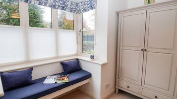 A corner room with a built-in bench, a window with a view, and a cabinet.