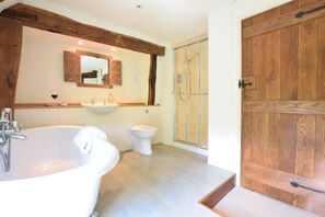 A bathroom with a large bathtub, a sink, a toilet, and a glass-enclosed shower. - Rectory Farm Cottage, Rougham (Bury St Edmunds)