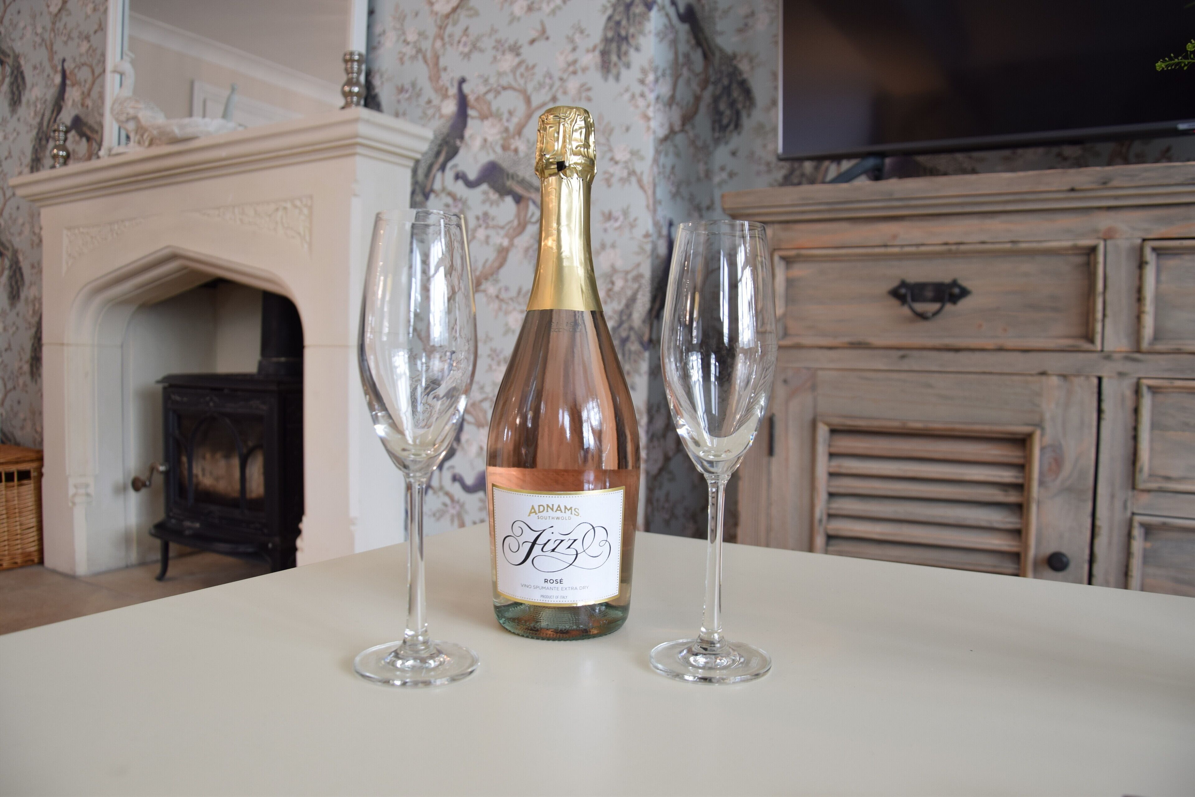 Una botella de vino Adnams Fizz sobre una mesa con dos copas de vino vacías.