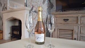 Una ampolla de vi Adnams Fizz sobre una taula amb dos vasos de vi buits.
