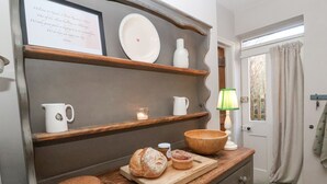 A kitchen counter with bread, a cutting board, and a sign above it. - Rosemary Cottage, Aldeburgh (Aldeburgh)