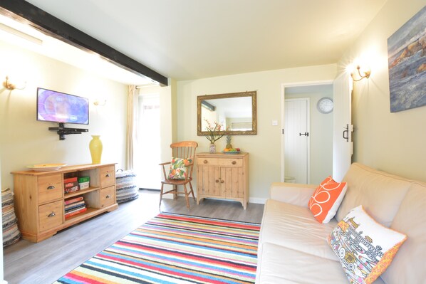 Un salon chaleureux avec un canapé, un tapis rayé aux couleurs vives, un meuble en bois et un téléviseur.
