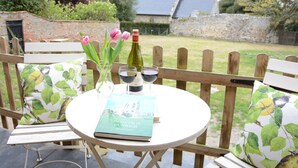 A round table with a book titled "The Lost City of Dunwich" by Nicholas Contis, two wine glasses, and a bottle of wine. - Church Farm Cottage, Dunwich (Saxmundham)