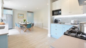 Une cuisine moderne avec des meubles de couleur bleu clair, une cuisinière en acier inoxydable et un coin repas comprenant une table et des chaises.