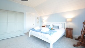 Une chambre à coucher avec un grand lit, une armoire, une table de chevet et une lampe.