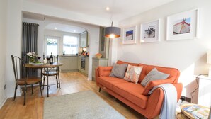 A modern living room with a sofa, a dining table with chairs, and a kitchen in the background. - 53 Tern Cottage, Aldeburgh (Aldeburgh)