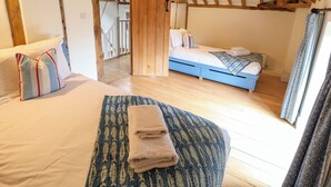 Une chambre avec un plafond en bois, un lit doté d’une tête de lit bleue et une fenêtre avec des rideaux.
