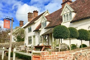 Un bâtiment traditionnel de couleur blanche, avec un toit recouvert de tuiles rouges, de nombreuses cheminées et une enseigne indiquant « Easton White Horse ».