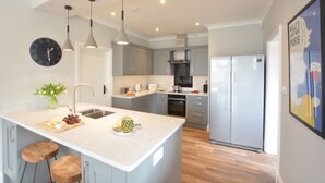 Una cocina moderna con una isla grande, electrodomésticos de acero inoxidable e iluminación colgante.